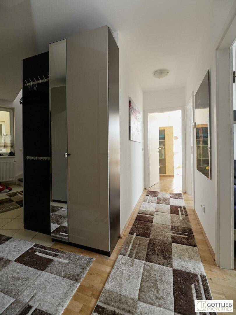 Heller Flur mit gemustertem Teppich und praktischem Spiegelschrank.