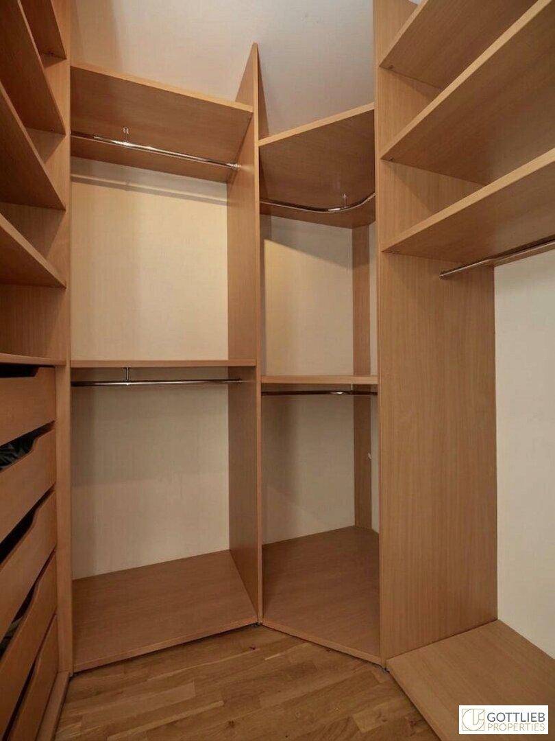 Praktischer begehbarer Kleiderschrank mit maßgefertigten Holzregalen und viel Stauraum.