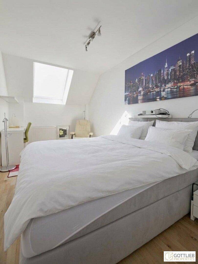Modernes Schlafzimmer mit großem Bett, Schreibtisch und Dachfenster für viel Tageslicht.