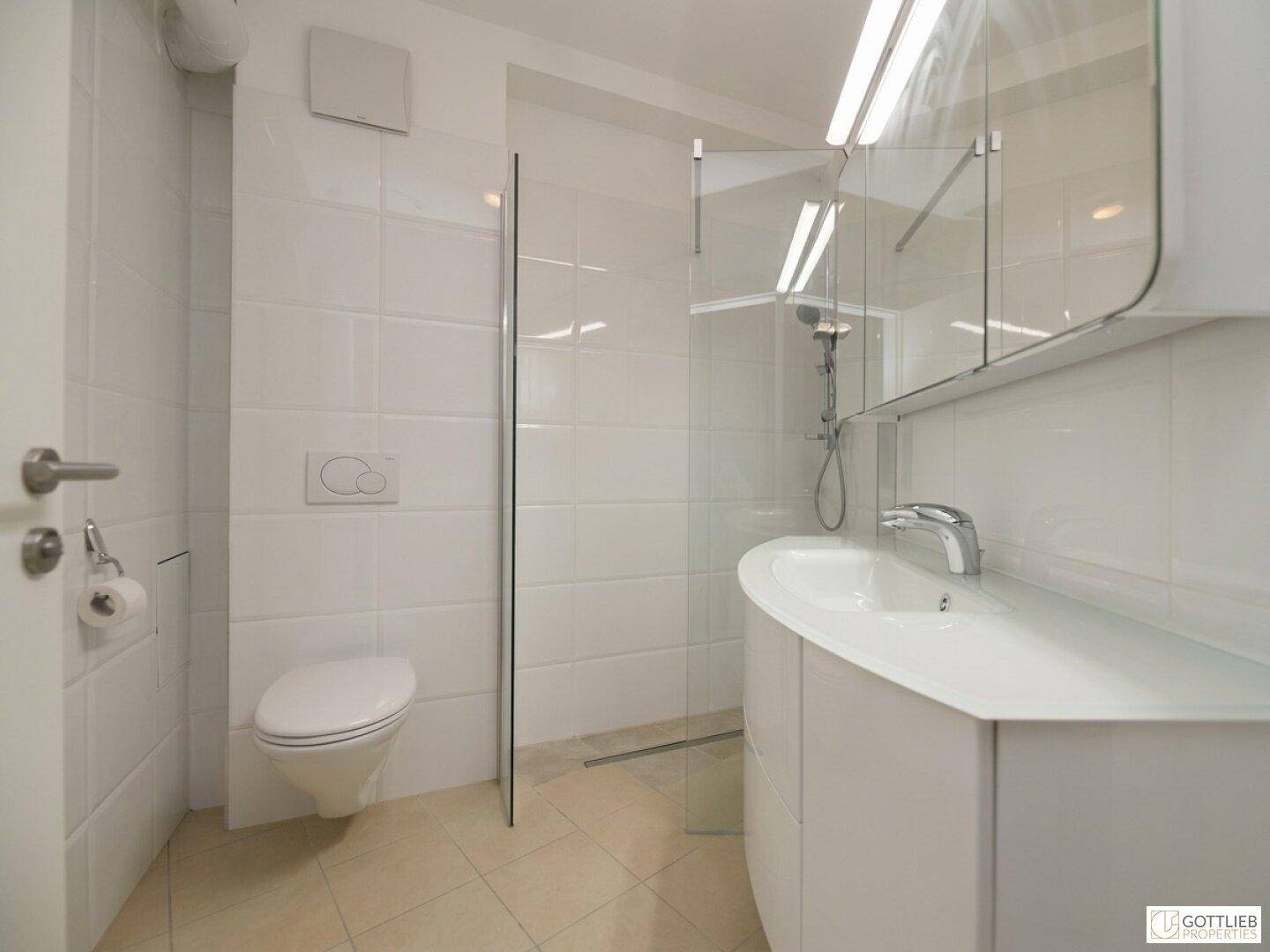 Modernes Badezimmer mit wandhängendem WC, begehbarer Dusche und elegantem Waschtisch.