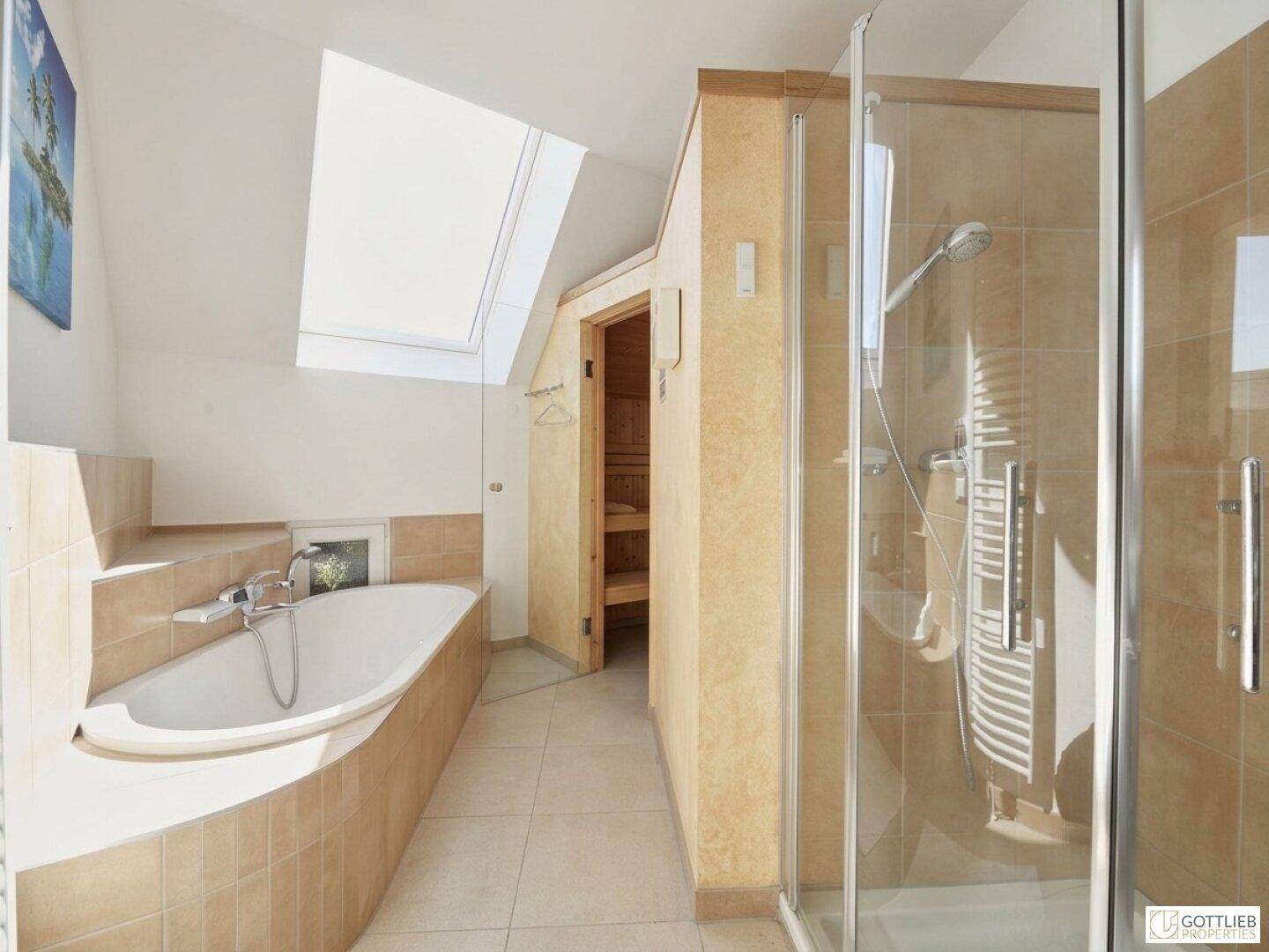 Geräumiges Badezimmer mit Badewanne, begehbarer Dusche und Zugang zur Sauna.