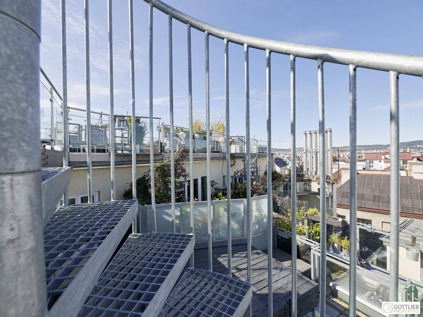 Metall-Wendeltreppe auf der Dachterrasse mit Blick auf die umliegenden Gebäude.