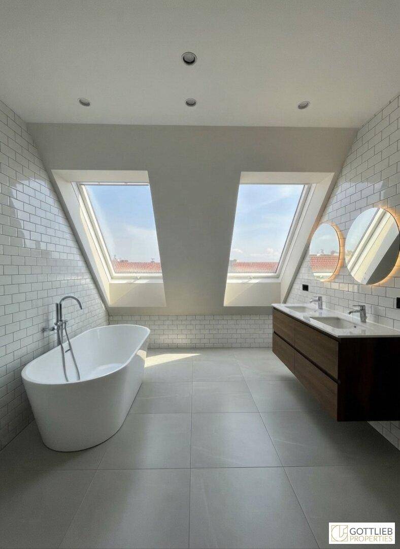 Modernes Badezimmer im Dachgeschoss mit freistehender Badewanne, Doppelwaschbecken und Dachfenstern.