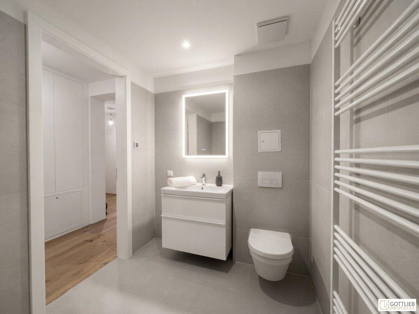Modernes Badezimmer mit schwebendem Waschtisch, beleuchtetem Spiegel und Wand-WC.