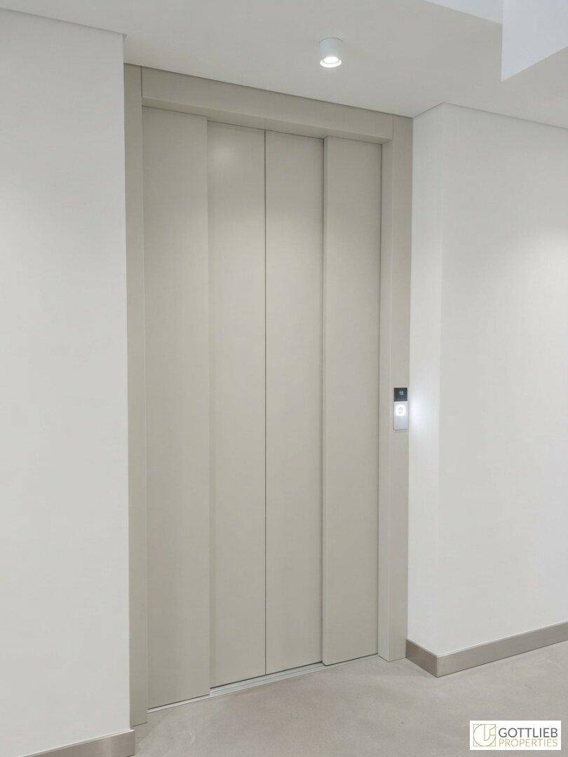 Moderner Aufzug in einem hellen Flur des Gebäudes, der Zugang zu den Etagen bietet.