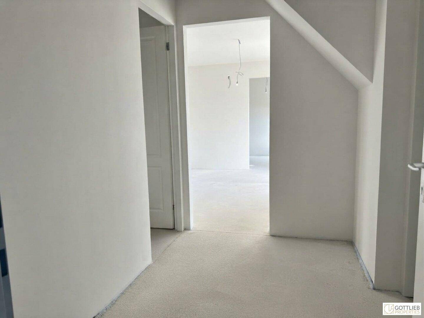 Leerer Flur mit weiß gestrichenen Wänden und Zugang zu weiteren Räumen im Apartment.