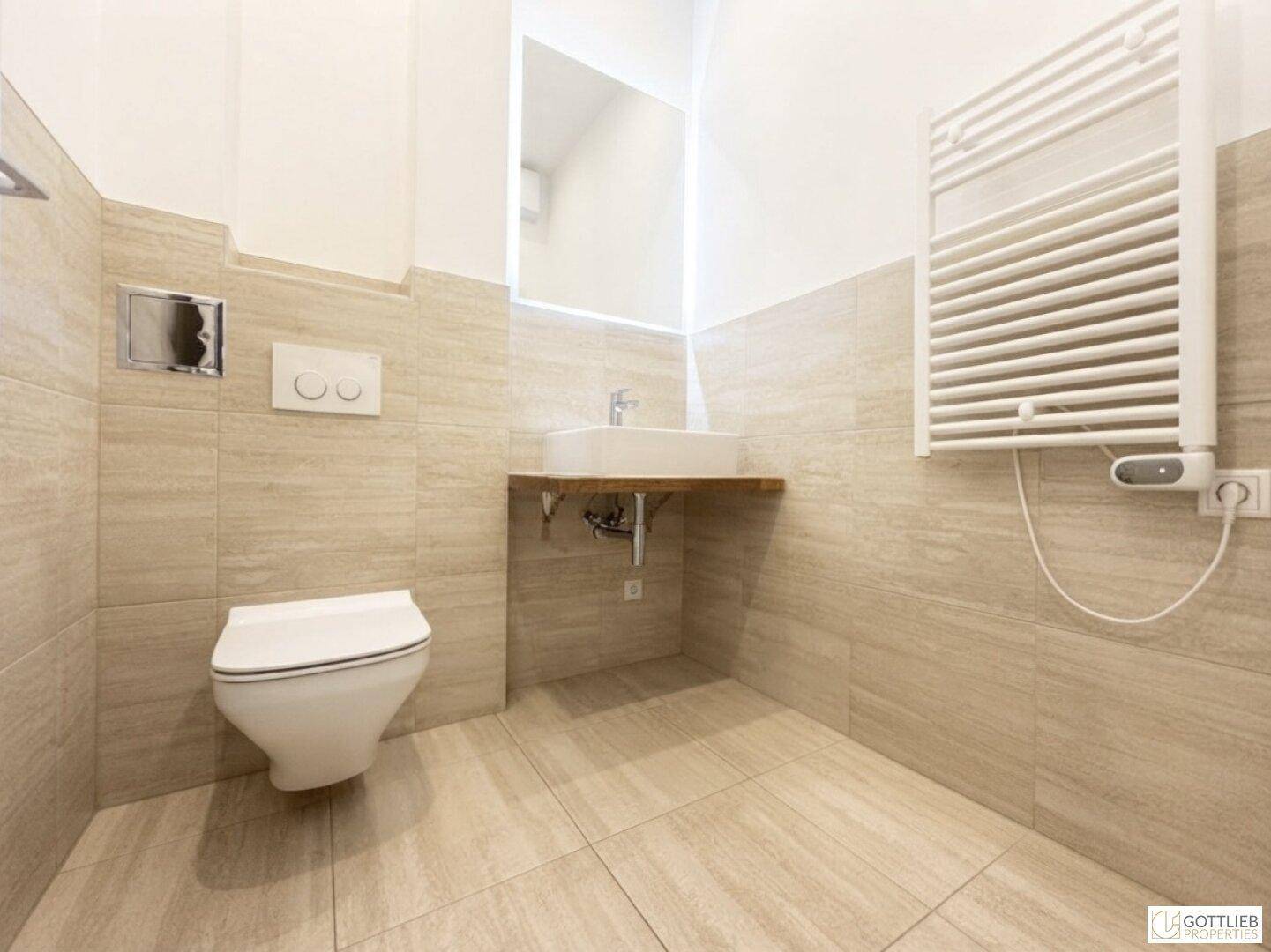 Modernes Badezimmer mit beigefarbenen Fliesen, wandhängendem WC und Waschbecken auf Holzablage.