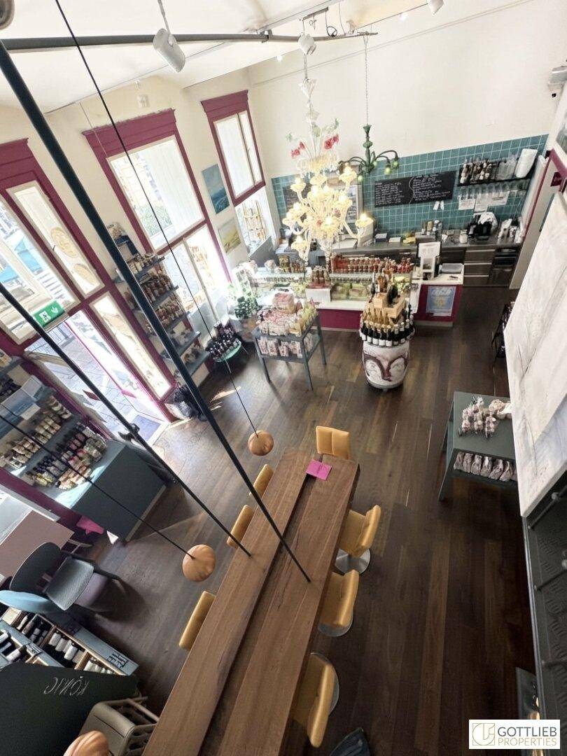 Blick von oben in einen hohen Verkaufsraum mit Holzboden, langer Theke und Regalen voller Produkte.