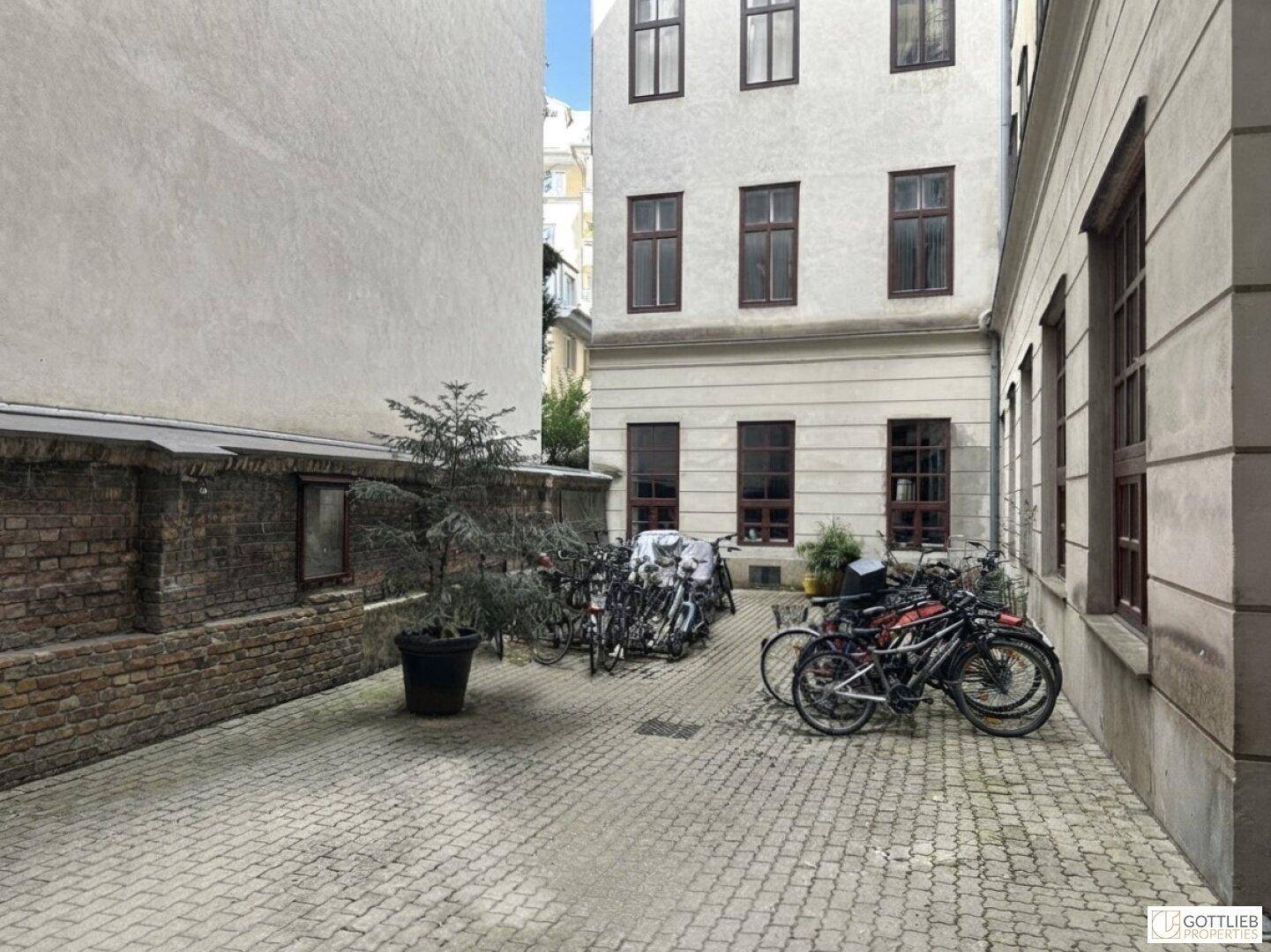 Innenhof mit Kopfsteinpflaster und zahlreichen abgestellten Fahrrädern vor einem Gebäude.