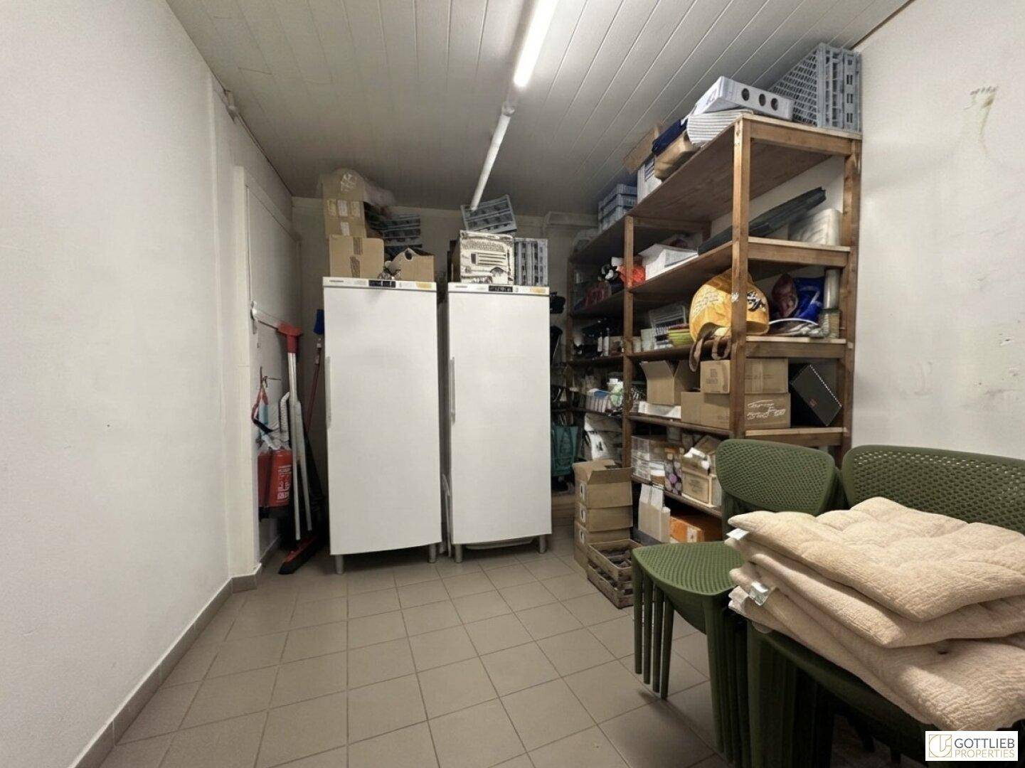 Lagerraum mit zwei großen Gefrierschränken und Holzregalen, gefüllt mit verschiedenen Vorräten.