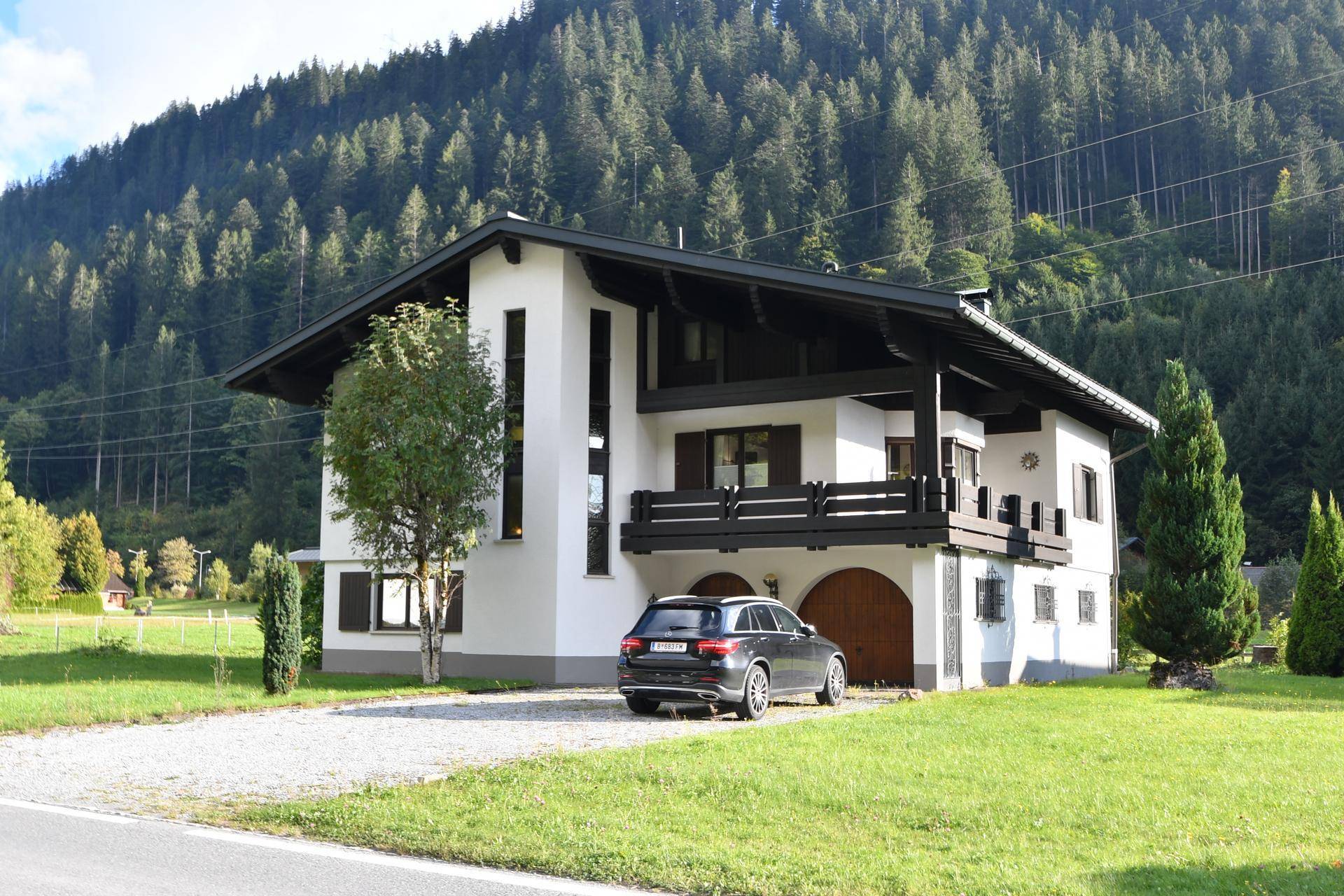 Modernisiertes Haus im alpinen Stil mit Garage, Balkon und Bergblick.