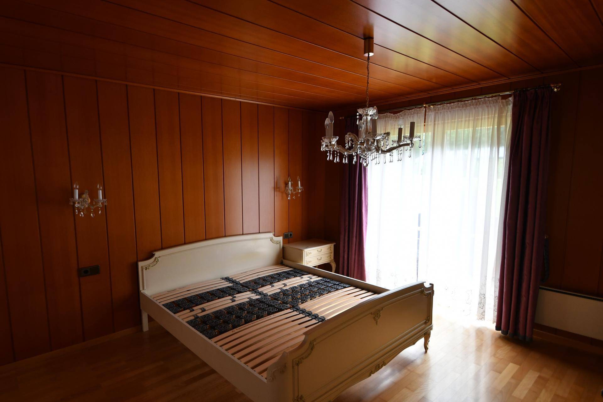 Schlafzimmer mit Holzwänden, Holzdecke und Zugang zu einem Balkon.