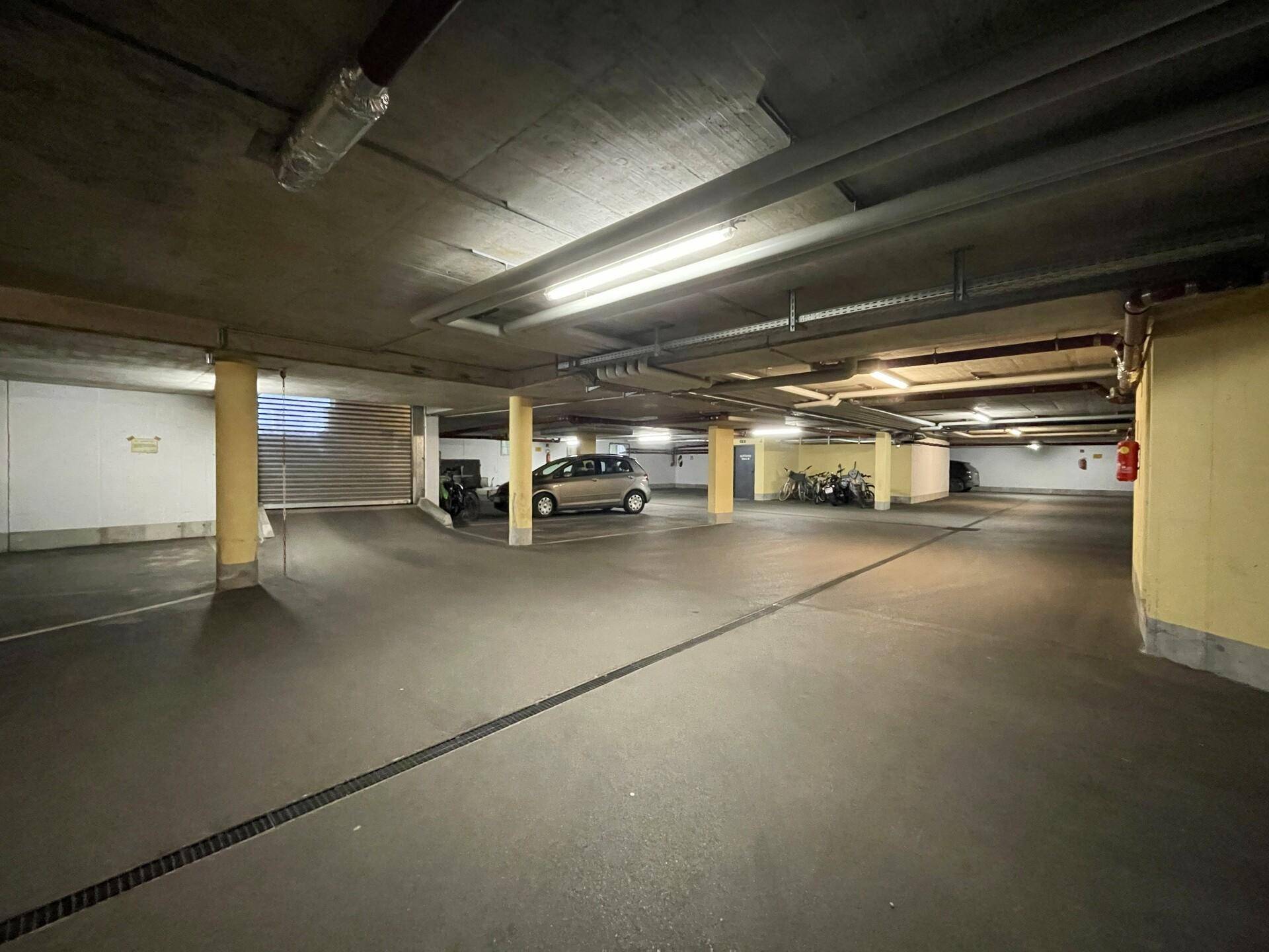Helle und saubere Tiefgarage mit ausreichend Platz für Fahrzeuge und Fahrräder.