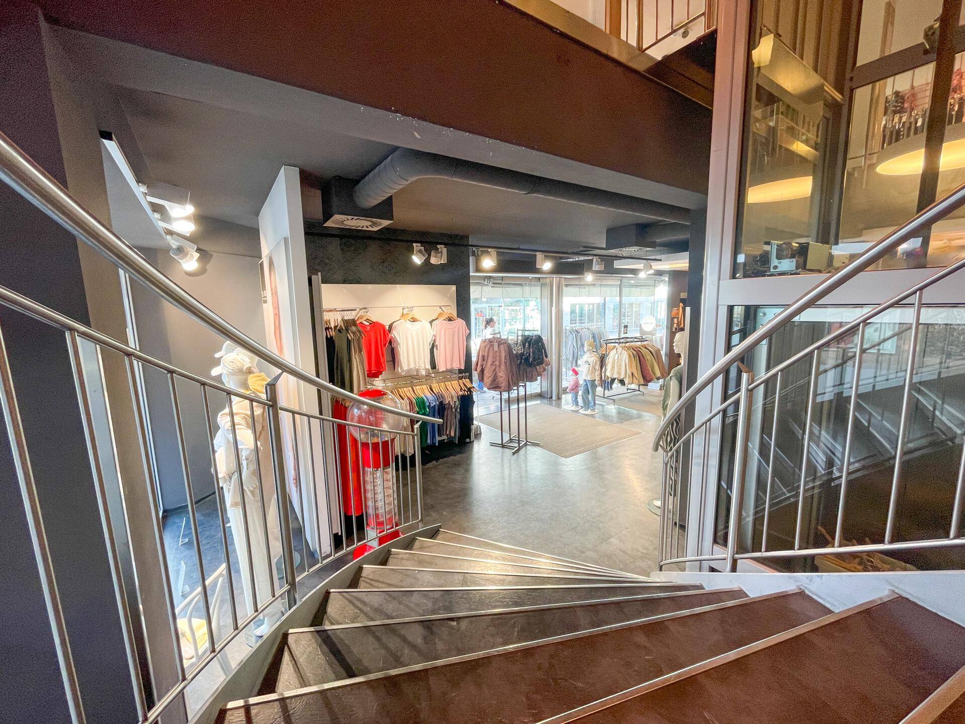 Wendeltreppe mit Metallgeländer in einem modernen Verkaufsraum, führt zu einer weiteren Etage.