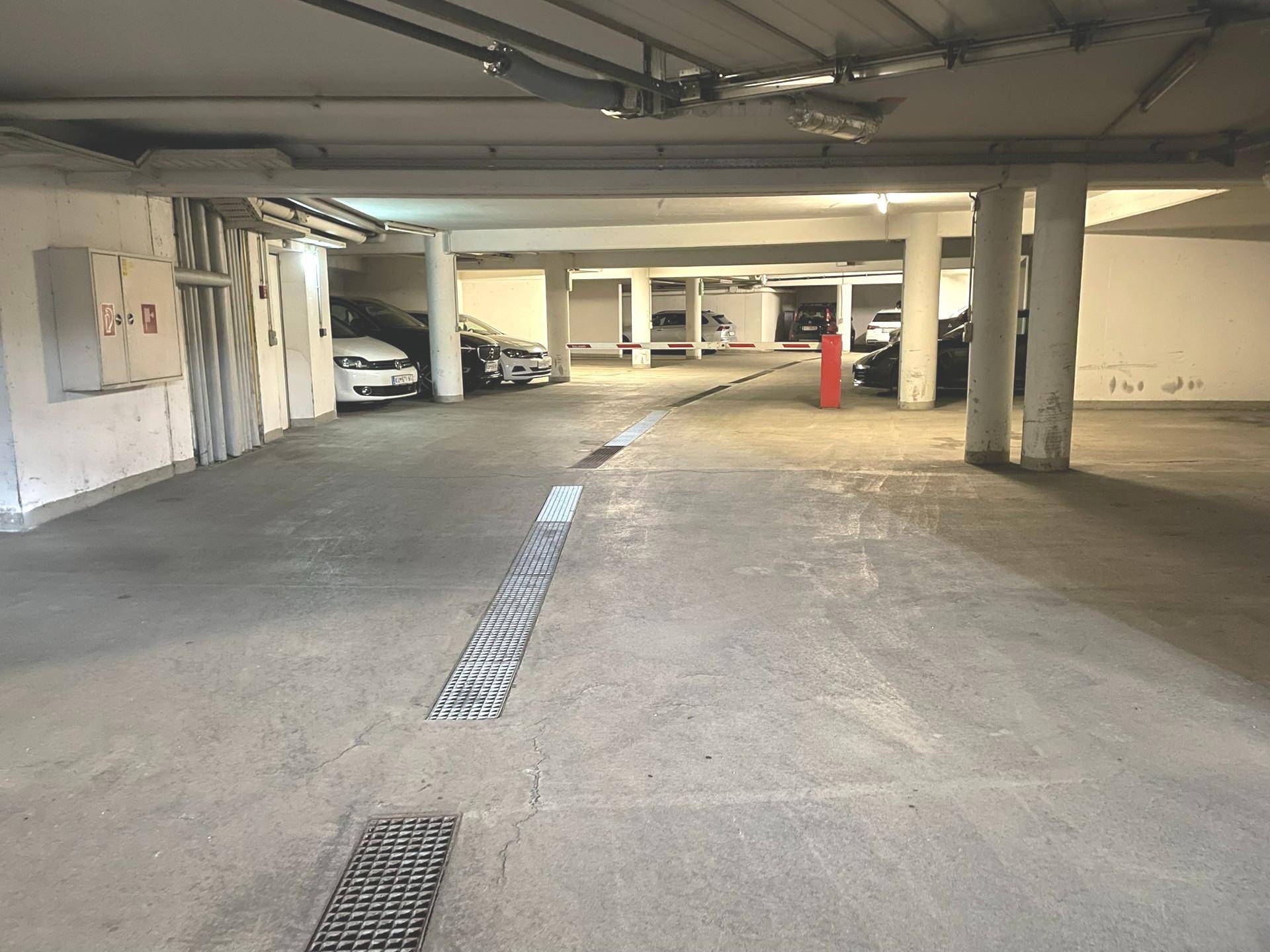 Blick durch die Tiefgarage mit weiteren Stellplätzen und der Zufahrt im Hintergrund.