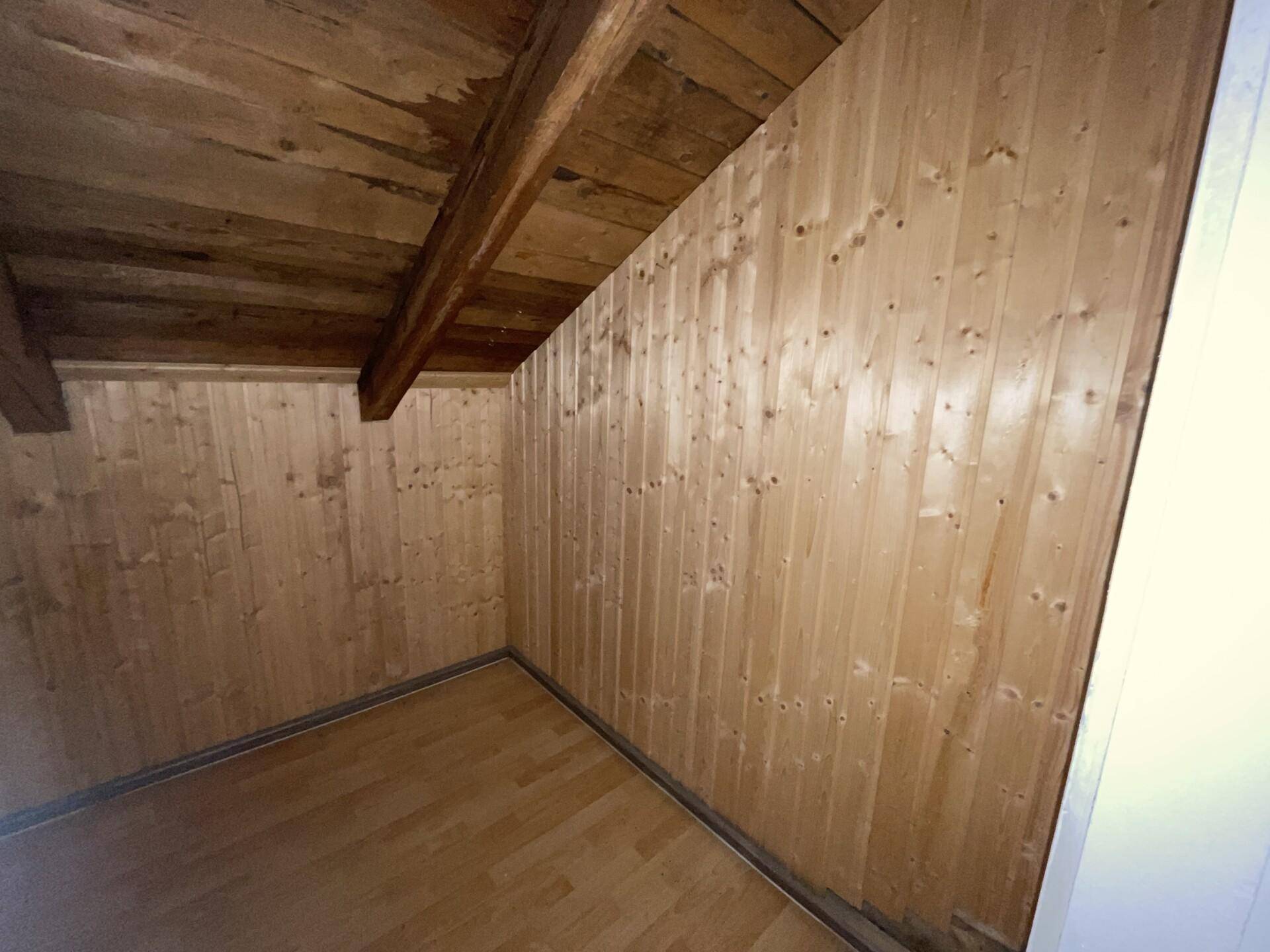 Kleiner Abstellraum mit Holzvertäfelung an den Wänden und hellem Holzfußboden.