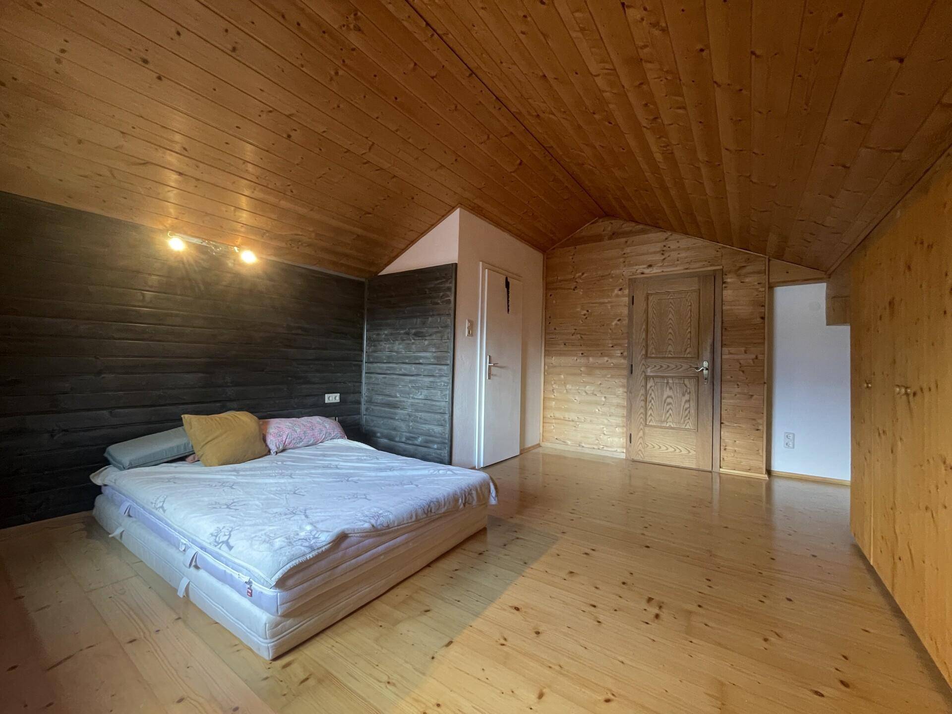 Schlafzimmer im Dachgeschoss mit Holzverkleidung, Holzboden und schrägen Decken.