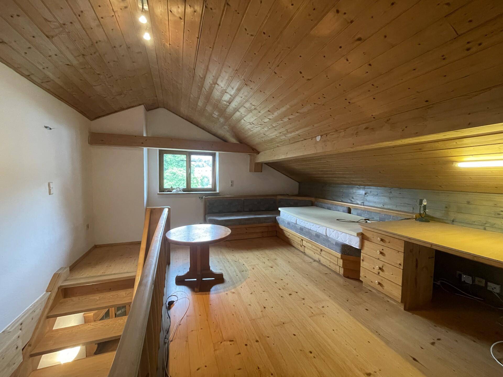 Gemütliches Schlafzimmer im Dachgeschoss mit Holzboden und integrierten Möbeln.