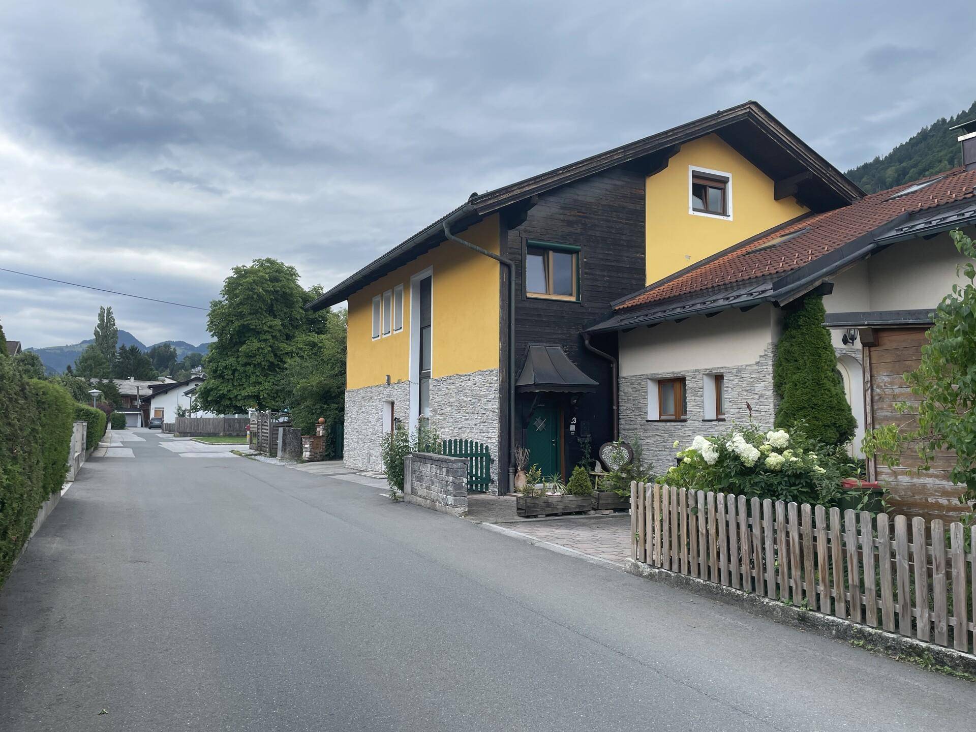 Wohnhaus mit gelber Fassade, Steinverkleidung und Blick auf die Straße.