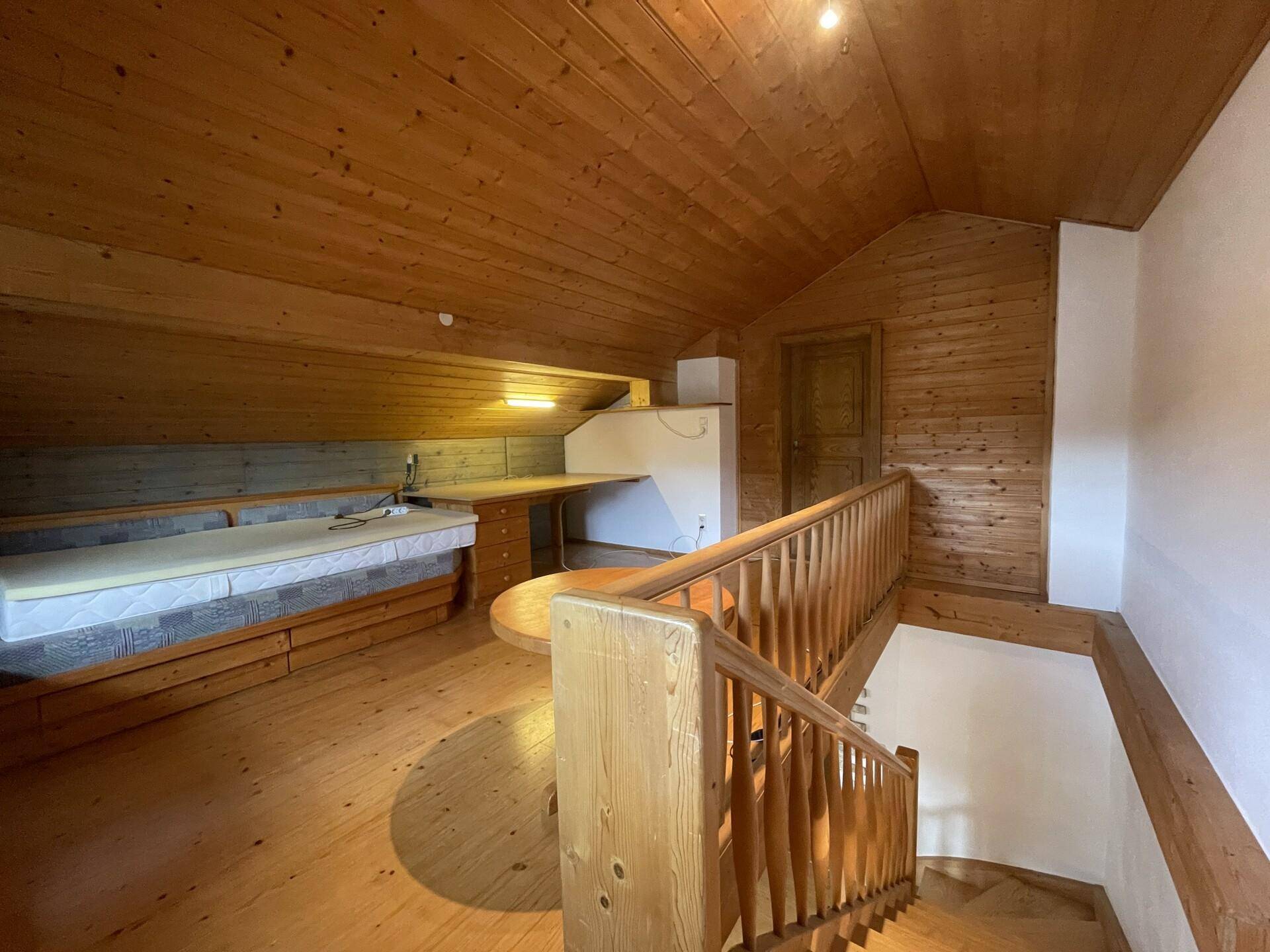 Dachgeschosszimmer mit Holzverkleidung, Holzboden und integriertem Stauraum.