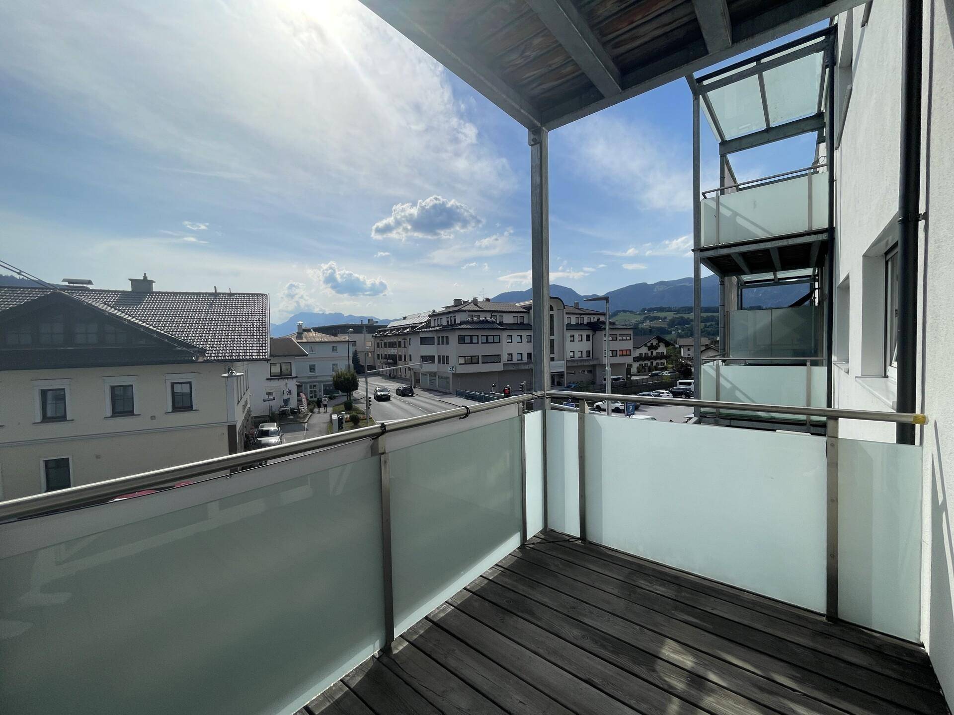 Sonniger Balkon mit weitem Blick über die Stadt und die Berglandschaft.