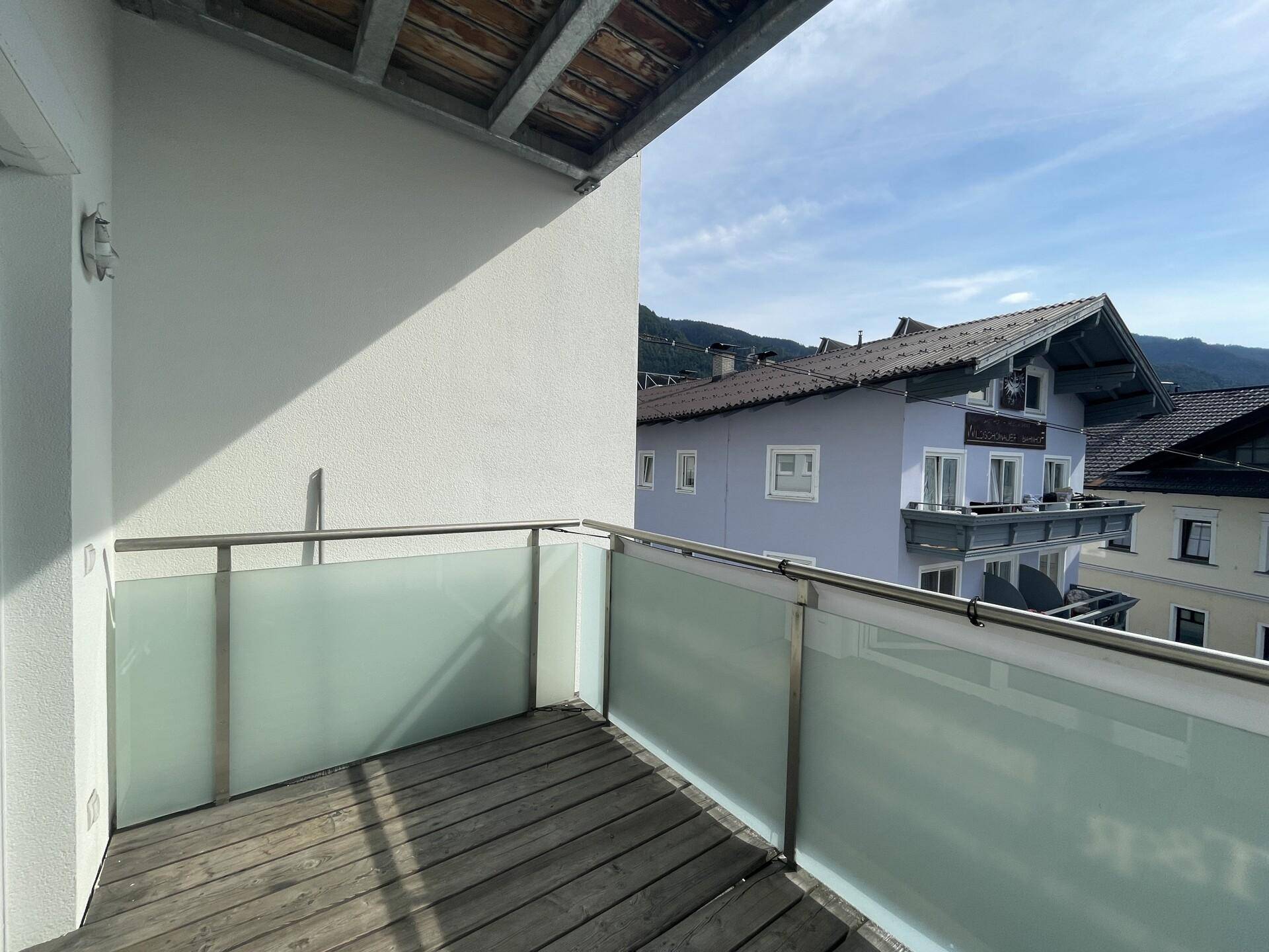Balkon mit Holzboden und Blick auf die umliegenden Häuser und Berge.