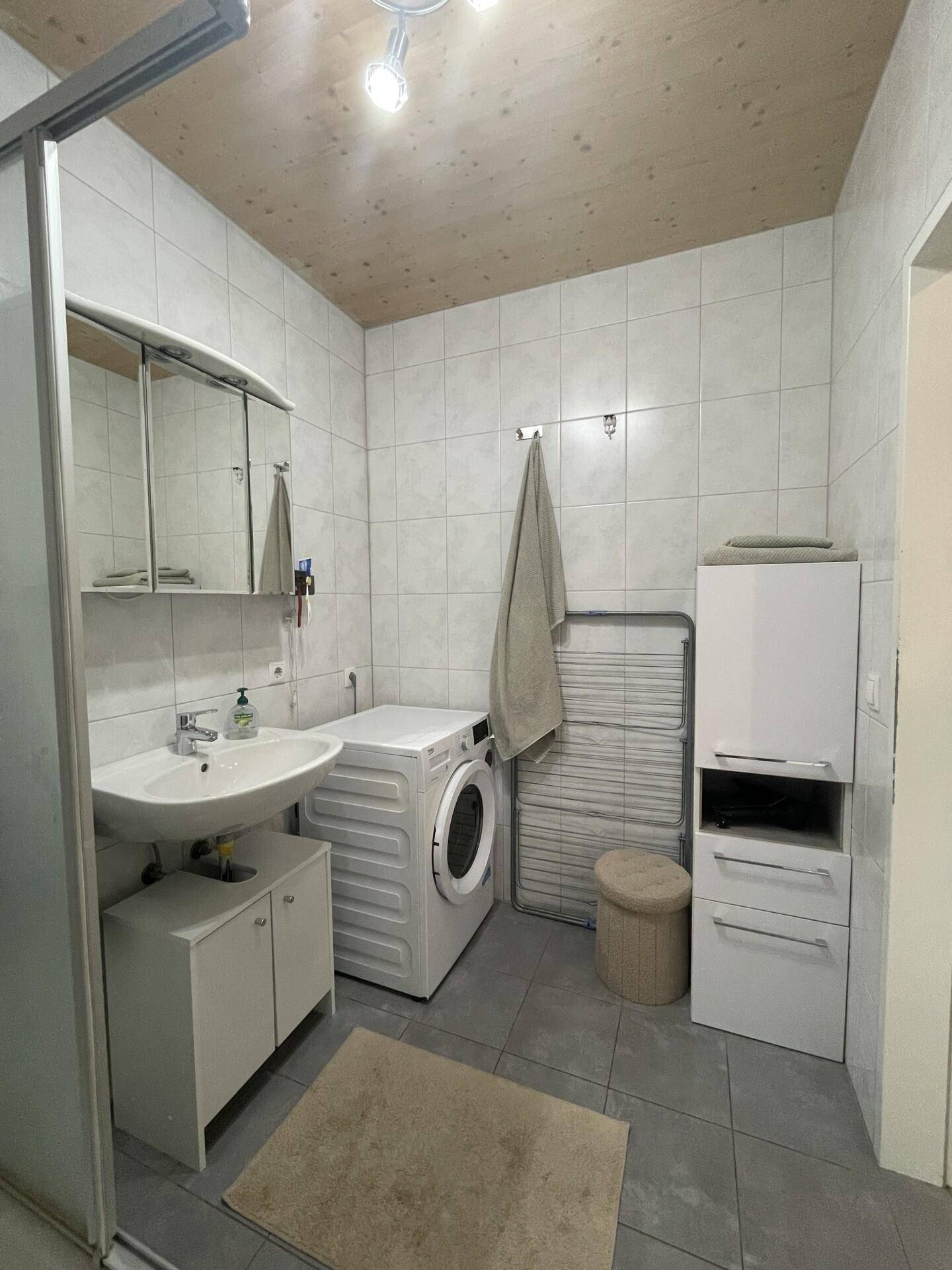 Modernes Badezimmer mit Dusche, Waschbecken und Waschmaschine.
