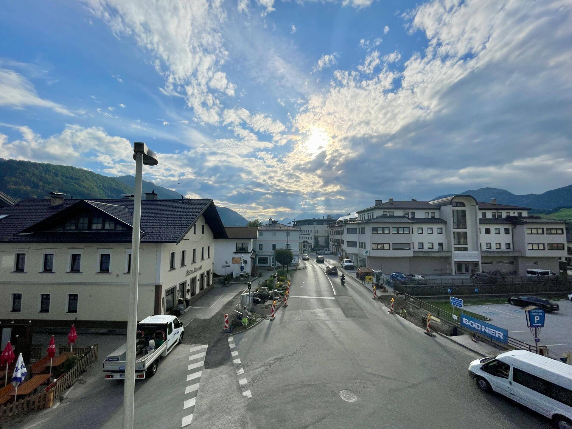 Weitläufiger Blick über die Stadtstraße mit Gebäuden und Bergen im Hintergrund.
