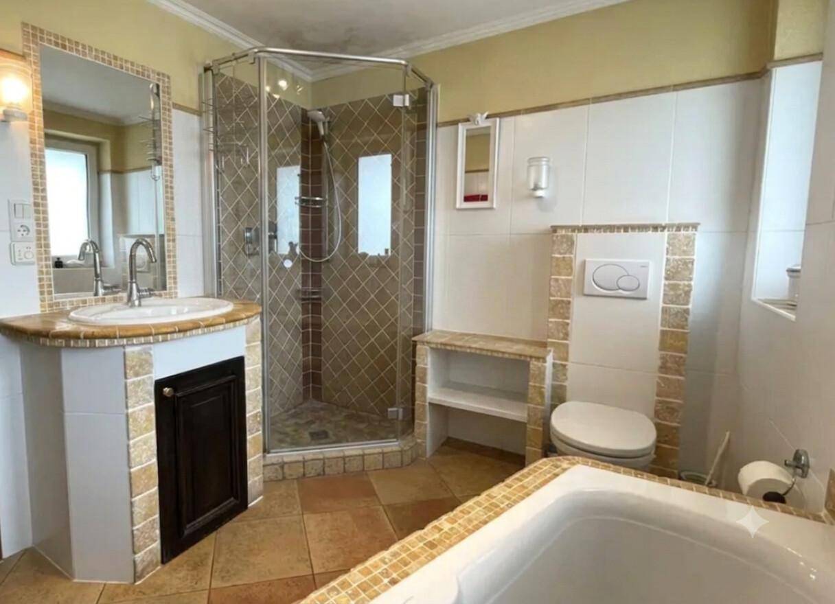Traditionelles Badezimmer mit Duschkabine, Badewanne und Waschtisch, hell und praktisch gestaltet.