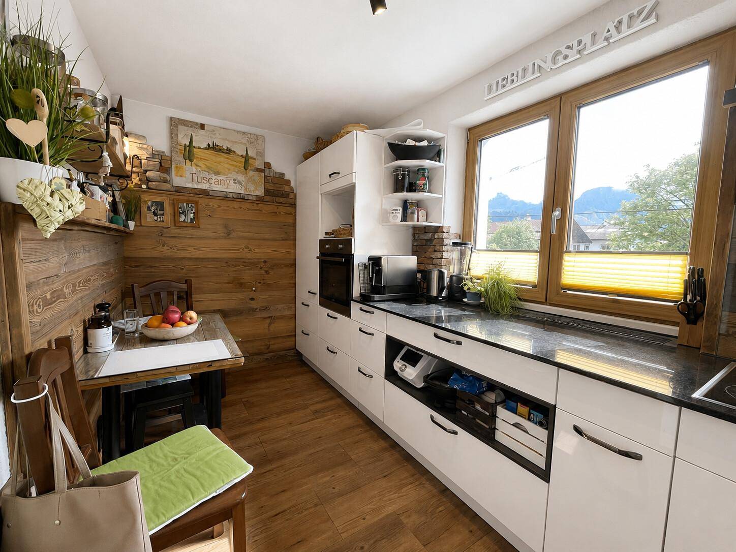 Gemütliche Wohnküche mit Essecke, Holzwänden und Blick auf die umliegende Landschaft.