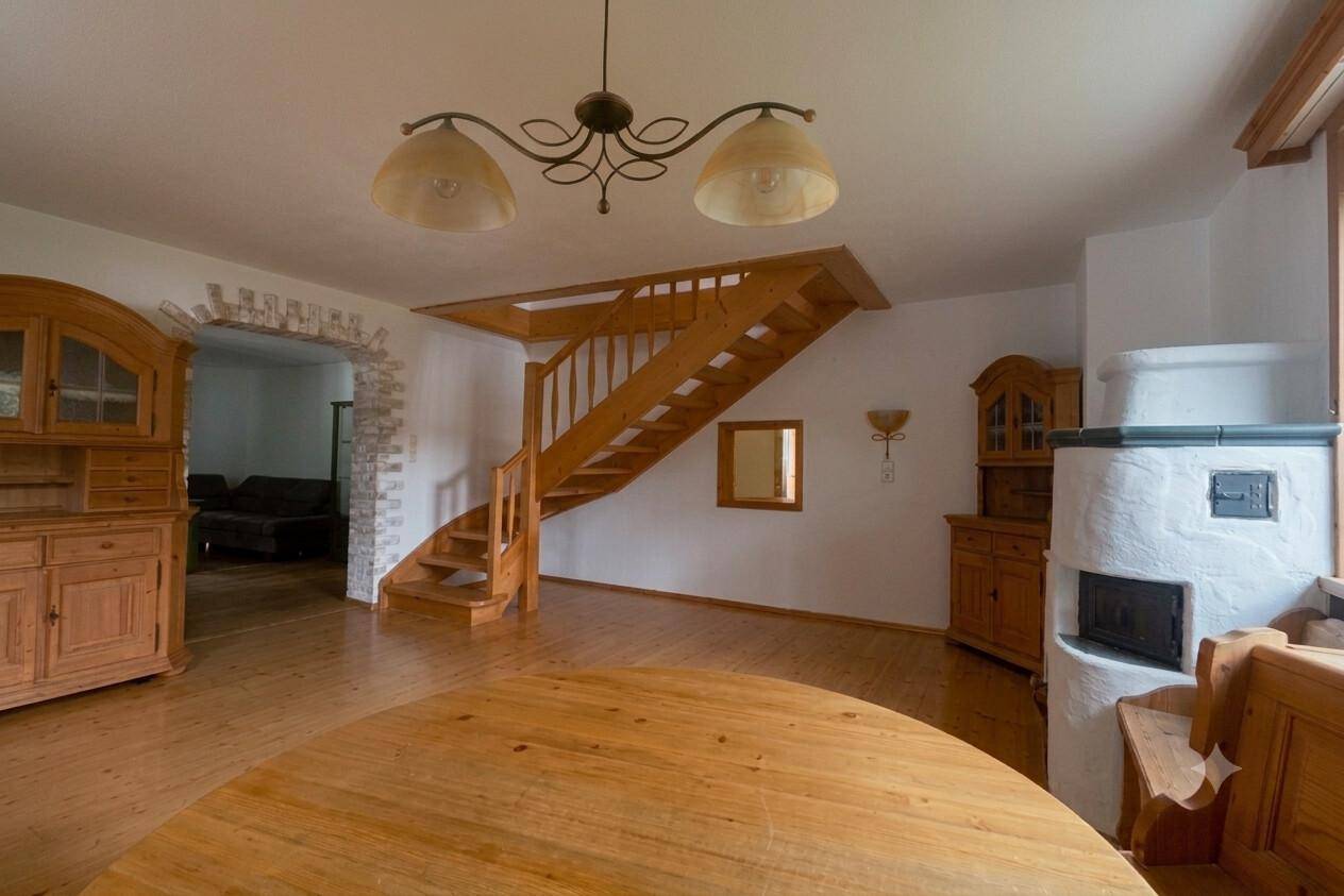 Heller Wohnbereich mit Holztreppe, Kachelofen und traditionellen Holzmöbeln, ideal für Familien.