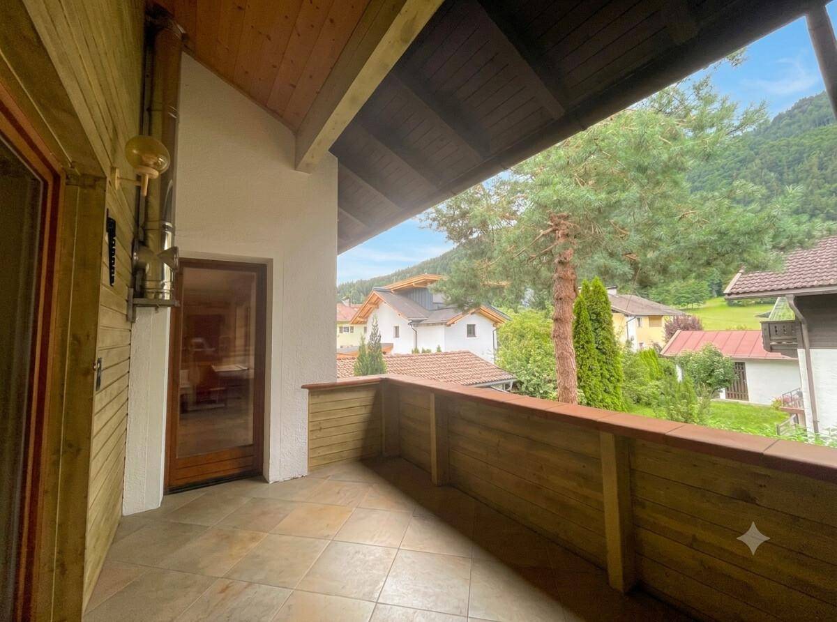 Überdachter Balkon mit Fliesenboden und weitem Blick auf die umliegende Berglandschaft.