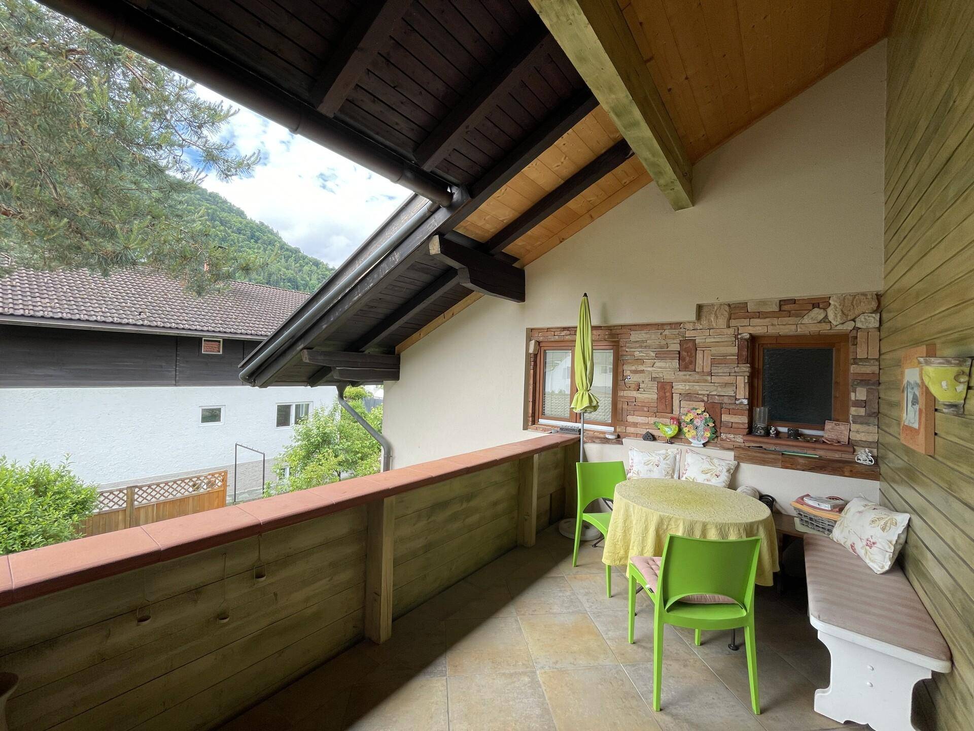Gemütlicher Balkon mit Sitzgelegenheiten, Sonnenschirm und Blick ins Grüne, perfekt zum Entspannen.