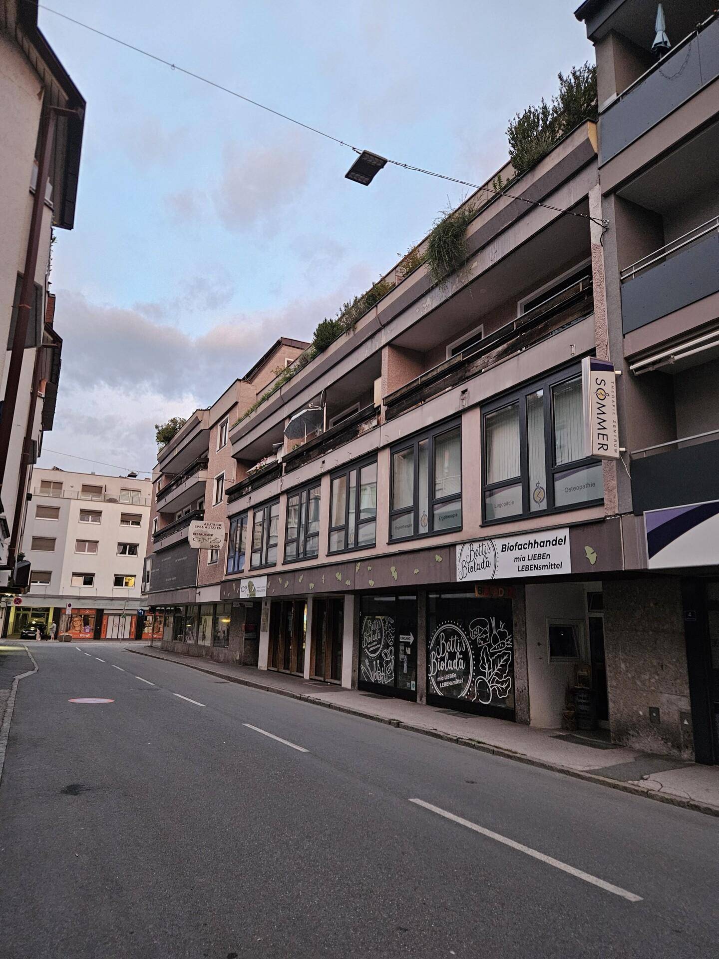 Gebäudeansicht von der Straße mit Geschäften im Erdgeschoss und Wohnungen darüber.