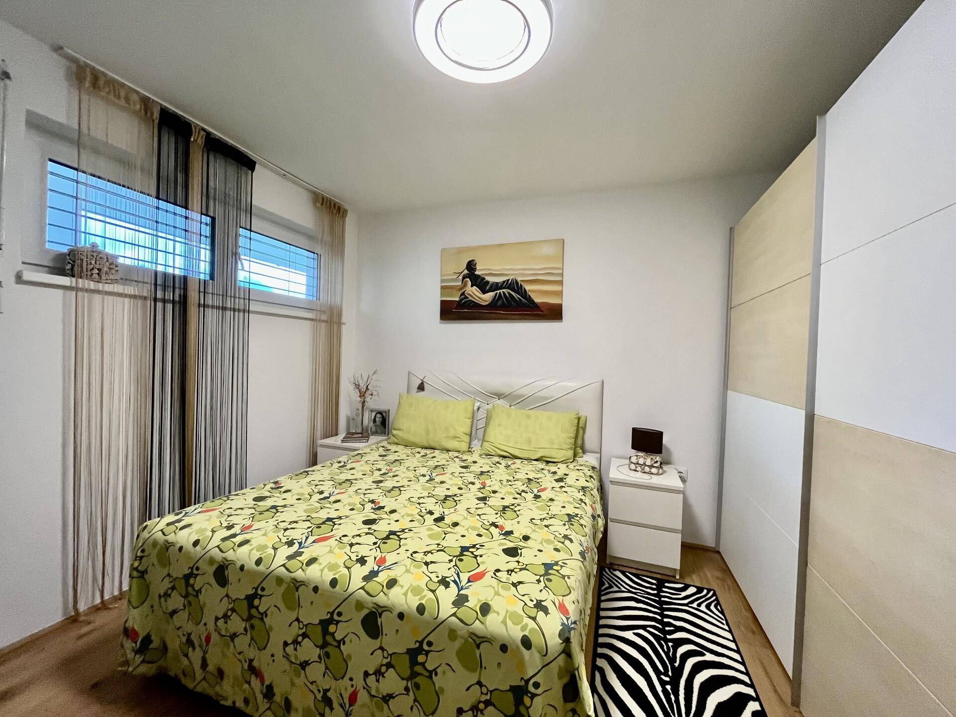 Helles Schlafzimmer mit Doppelbett, Nachttischen und großem Kleiderschrank.