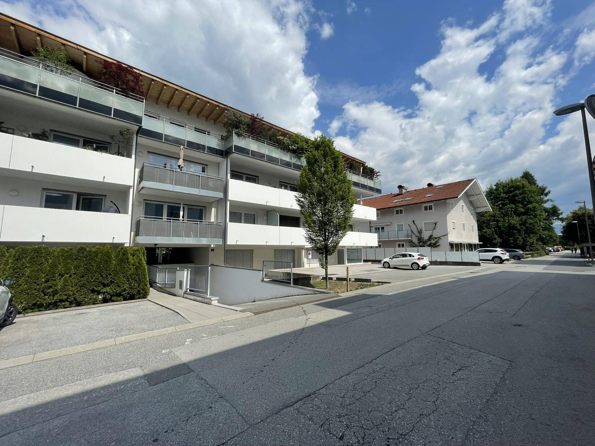 Moderne Wohnanlage mit Balkonen, Tiefgaragenzufahrt und gepflegter Außenansicht.