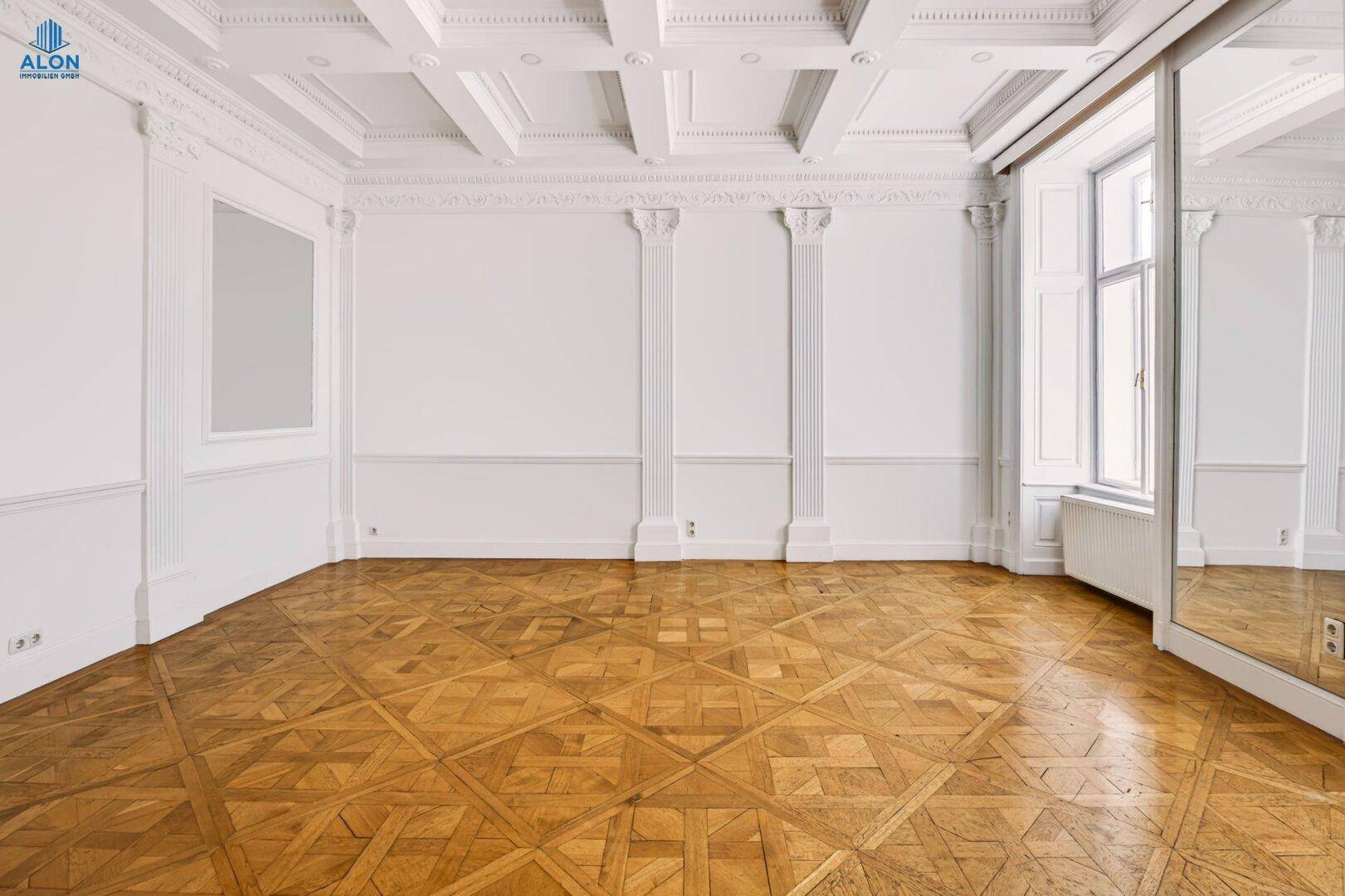 Geräumiges Zimmer mit Kassettendecke, Parkettboden und großen Fenstern, die viel Tageslicht bieten.