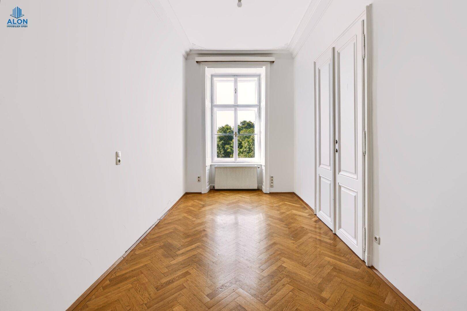 Helles Schlafzimmer mit Fischgrätparkett, hohen Decken und Fenster mit Grünblick, sehr gepflegt.