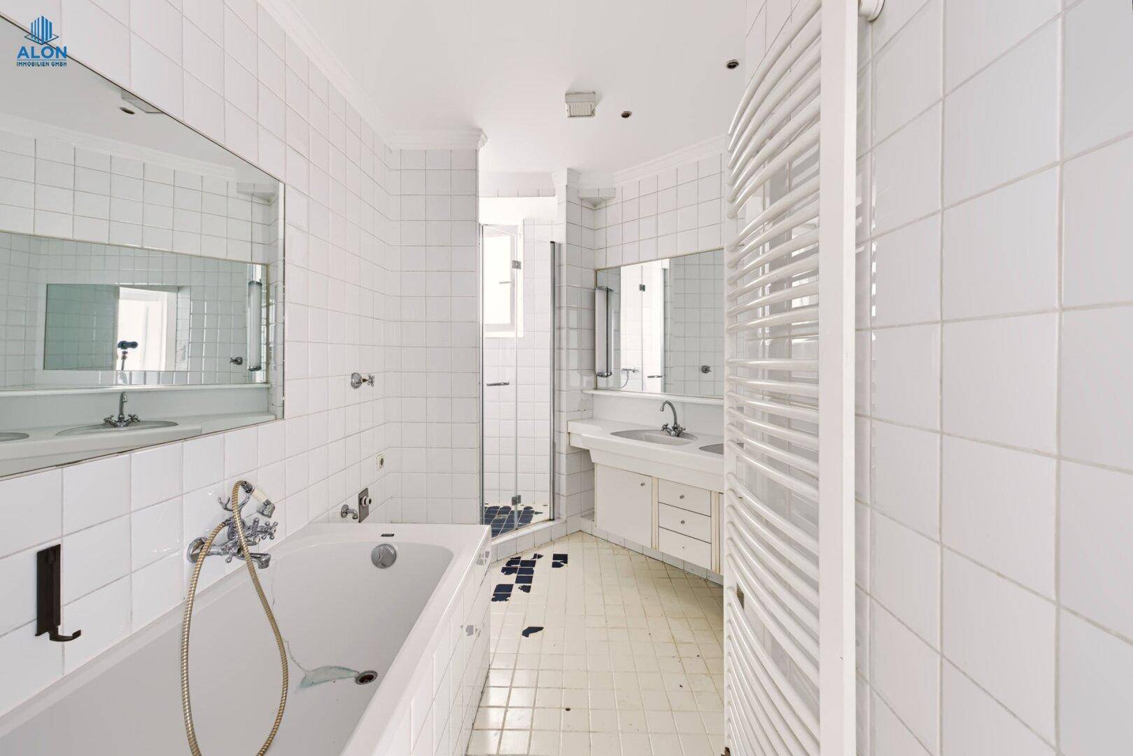 Helles Badezimmer mit Badewanne, Dusche, Doppelwaschbecken und weißen Fliesen, sehr gepflegt.
