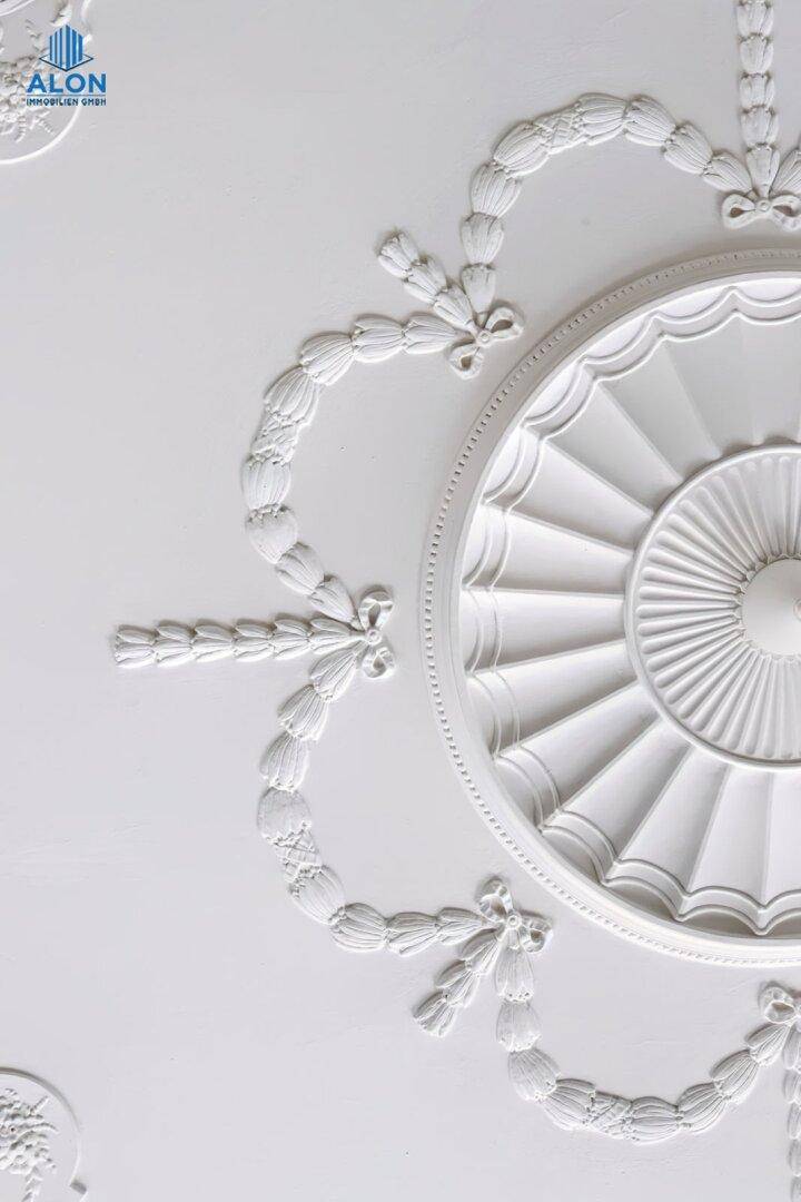Nahaufnahme eines runden Stuckmedaillons an einer eleganten Decke, ein Zeichen von Handwerkskunst.