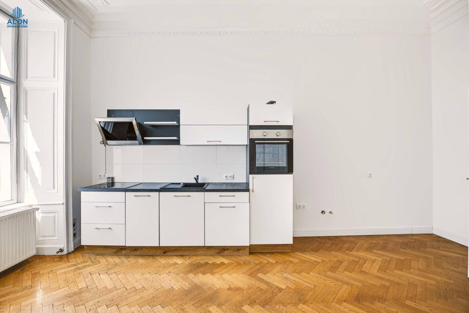Moderne weiße Einbauküche mit dunkler Arbeitsplatte und integriertem Backofen, bereit zur Nutzung.