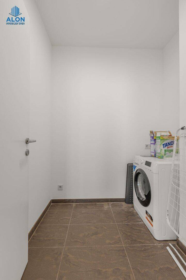 Praktischer Hauswirtschaftsraum mit Waschmaschine und Fliesenboden, bietet zusätzlichen Stauraum.