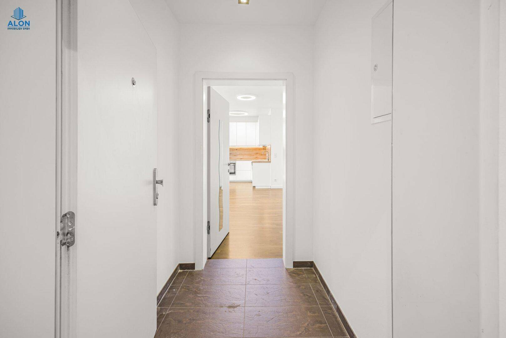 Eingangsbereich mit Fliesenboden und Blick in den offenen Wohnbereich, hell und modern gestaltet.