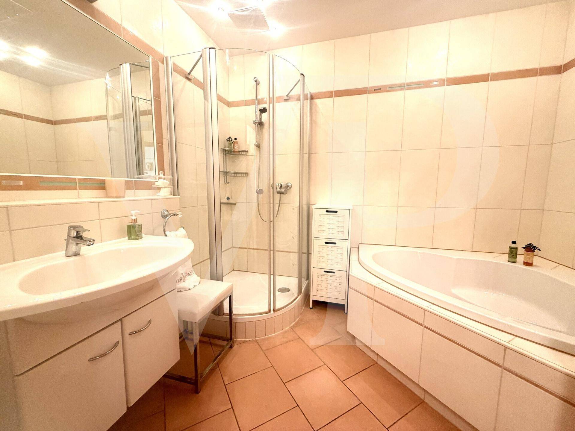 Funktionales Badezimmer mit Eckdusche, Badewanne und einem einzelnen Waschbecken, komplett gefliest.