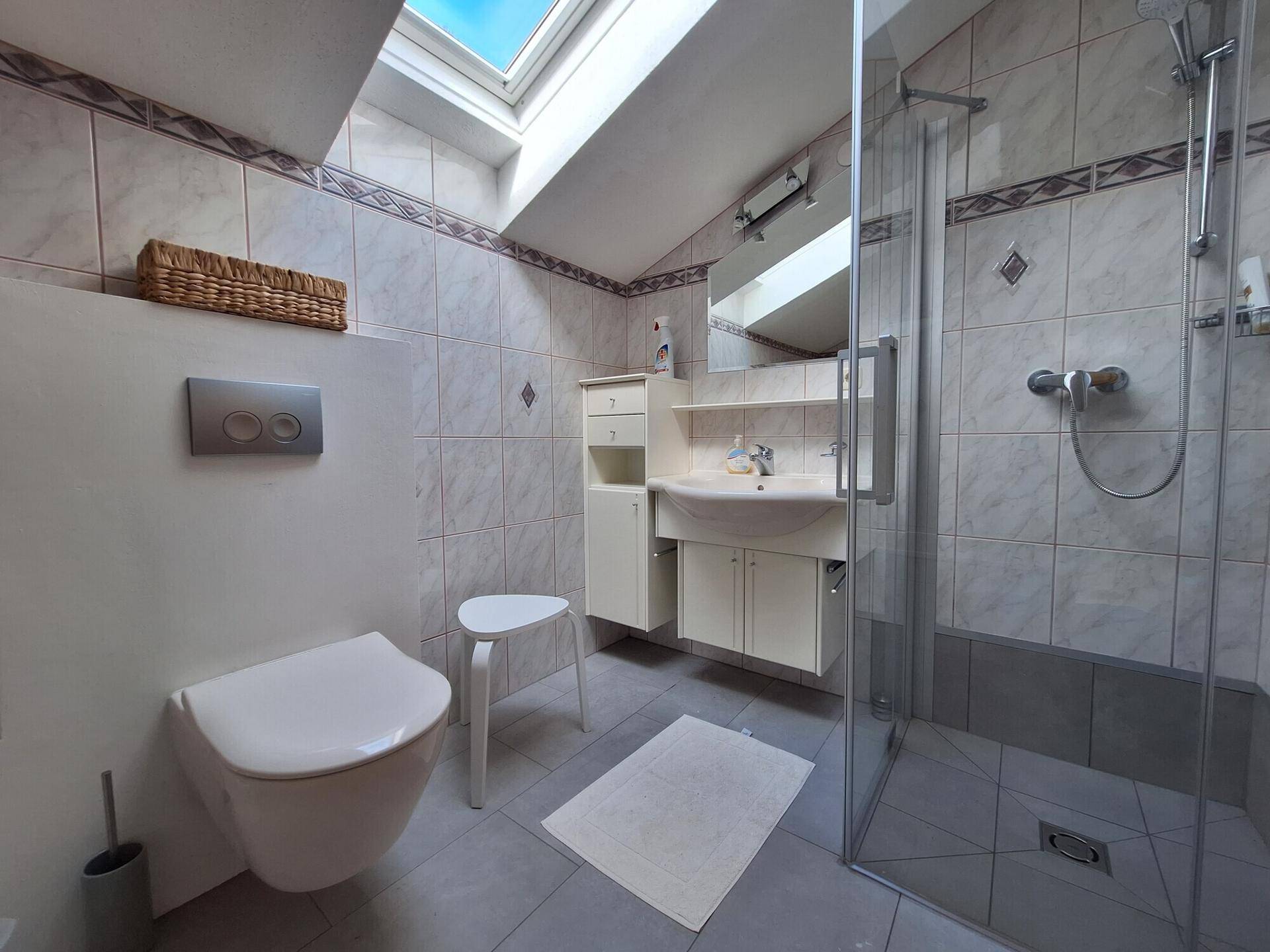 Helles Badezimmer im Dachgeschoss mit Dachfenster, Dusche und traditionellen Fliesen.