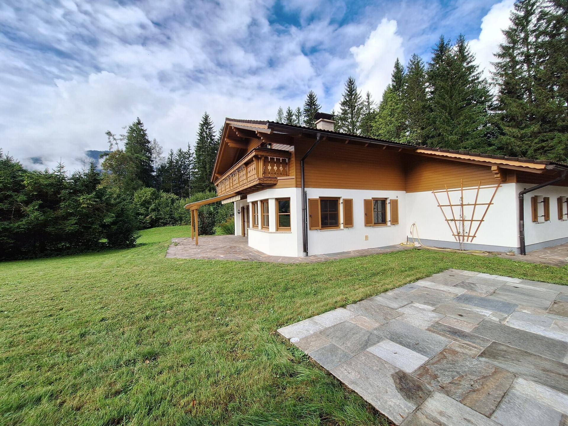 Traditionelles Haus im alpenländischen Stil mit großem Garten, Terrasse und Bergblick.