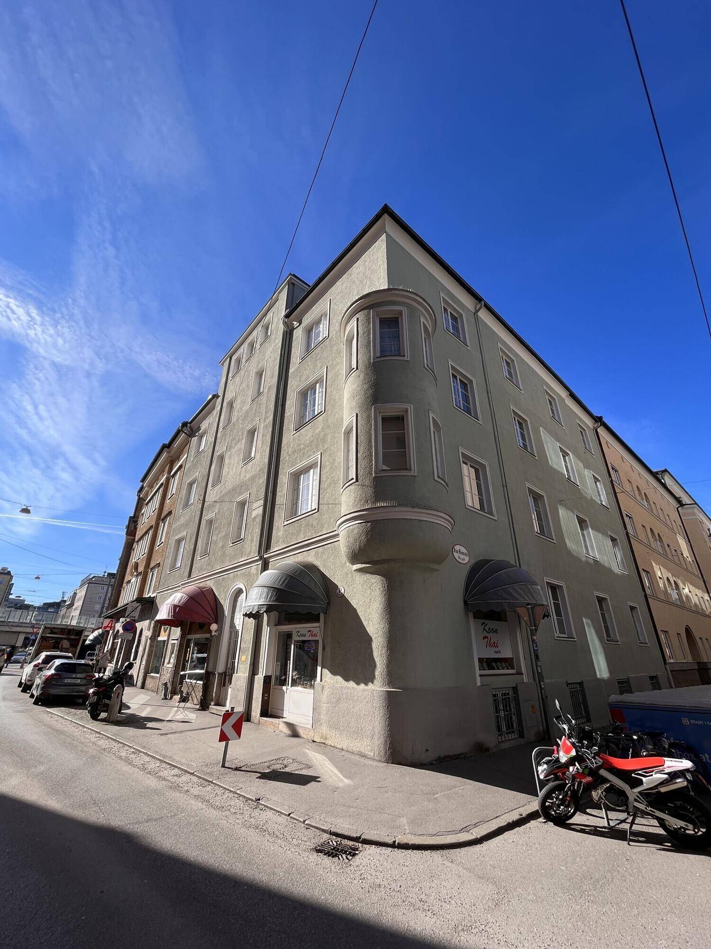 Eckgebäude an einer Straße mit Geschäften im Erdgeschoss und Wohnungen darüber, städtisch.