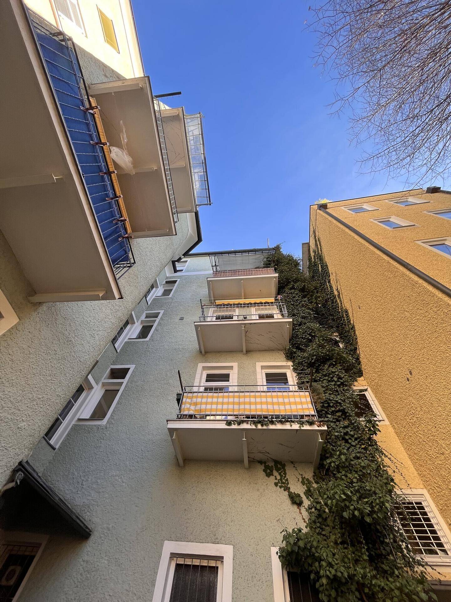 Fassade eines Wohngebäudes mit mehreren Balkonen und Kletterpflanzen, charmant und grün.