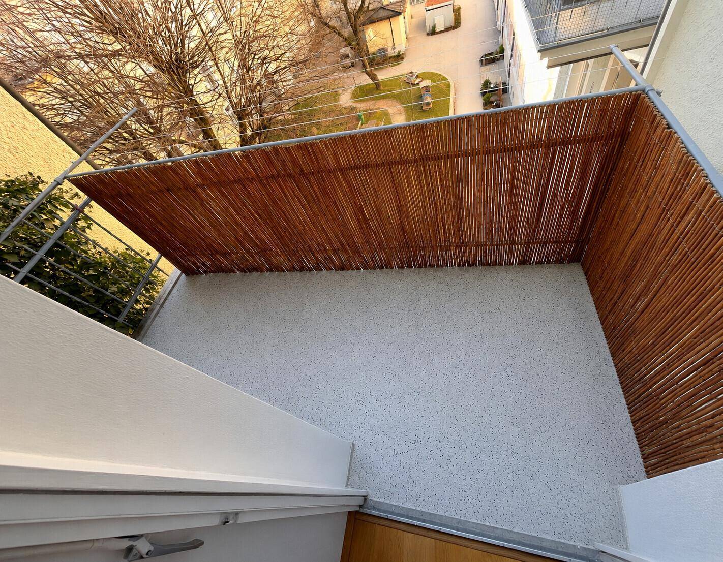 Kleiner Balkon mit Holzsichtschutz und Blick auf den Innenhof, ideal für Entspannung.