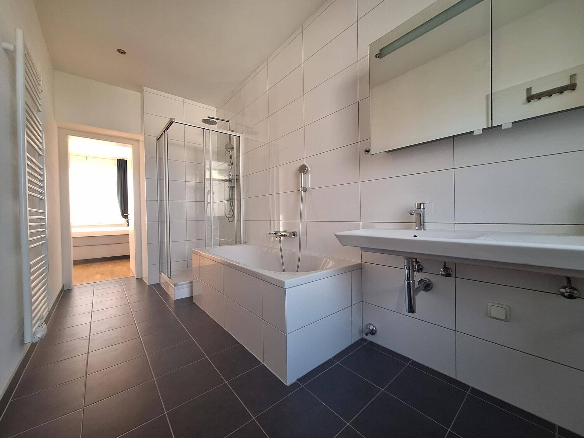 Modernes Badezimmer mit Badewanne, Duschkabine und großformatigen Fliesen, sehr gepflegt.